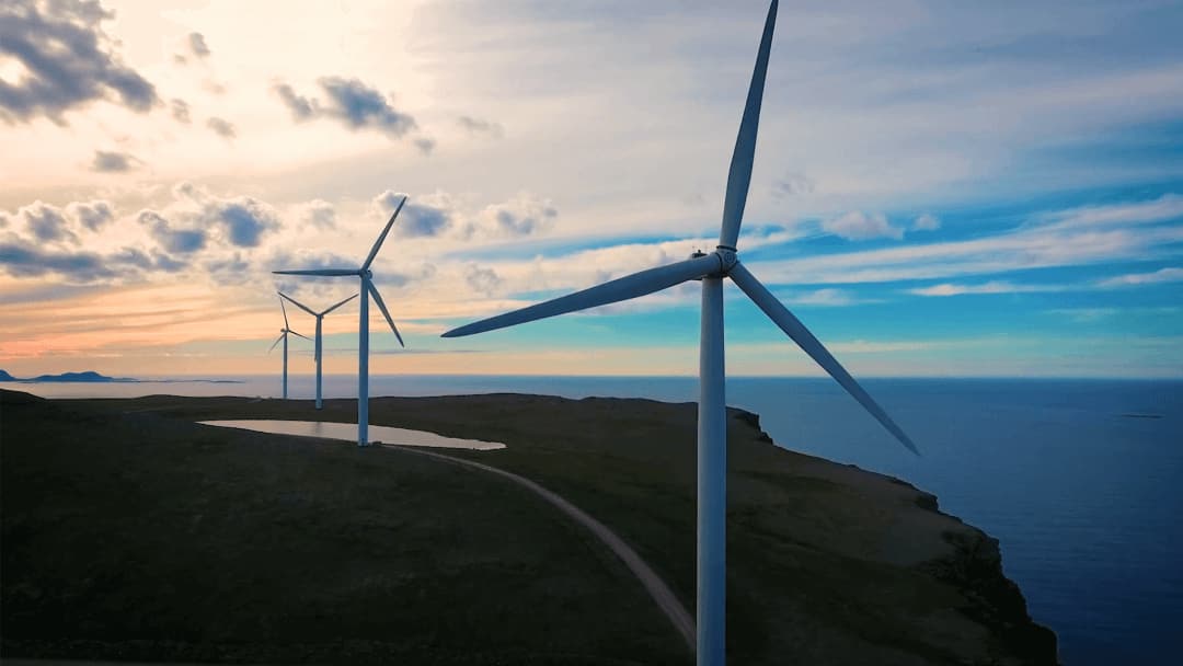 3 wind turbines pictured on land at the edge of a cliff