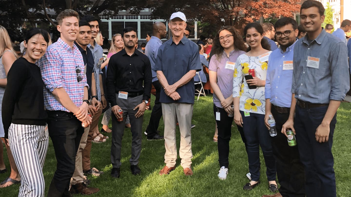 Akamai CEO and Co-Founder Tom Leighton stands in the center of a group of interns outside on the grass.